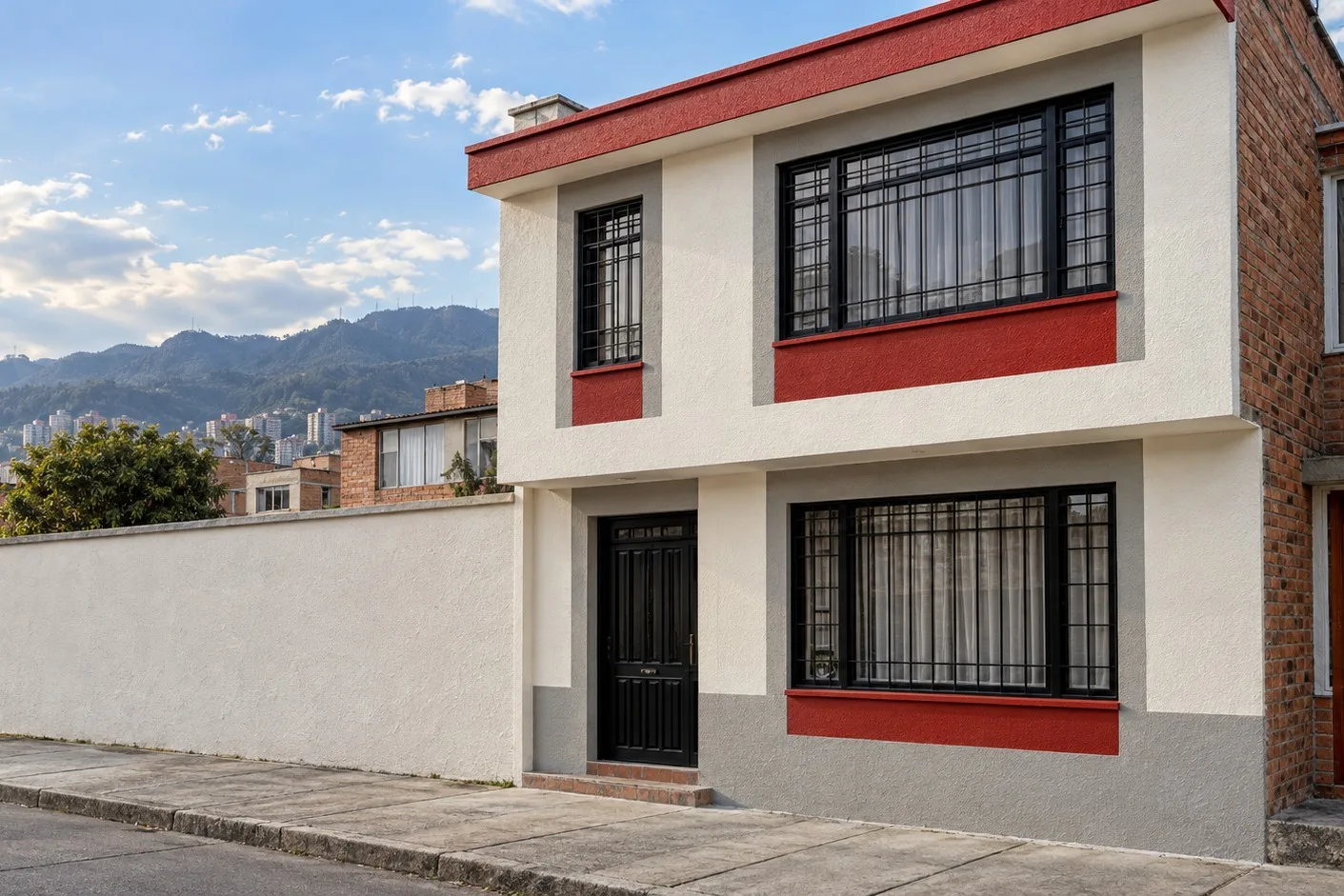 Fachada de vivienda recién pintada en blanco, rojo y gris sobre calle de Bogotá